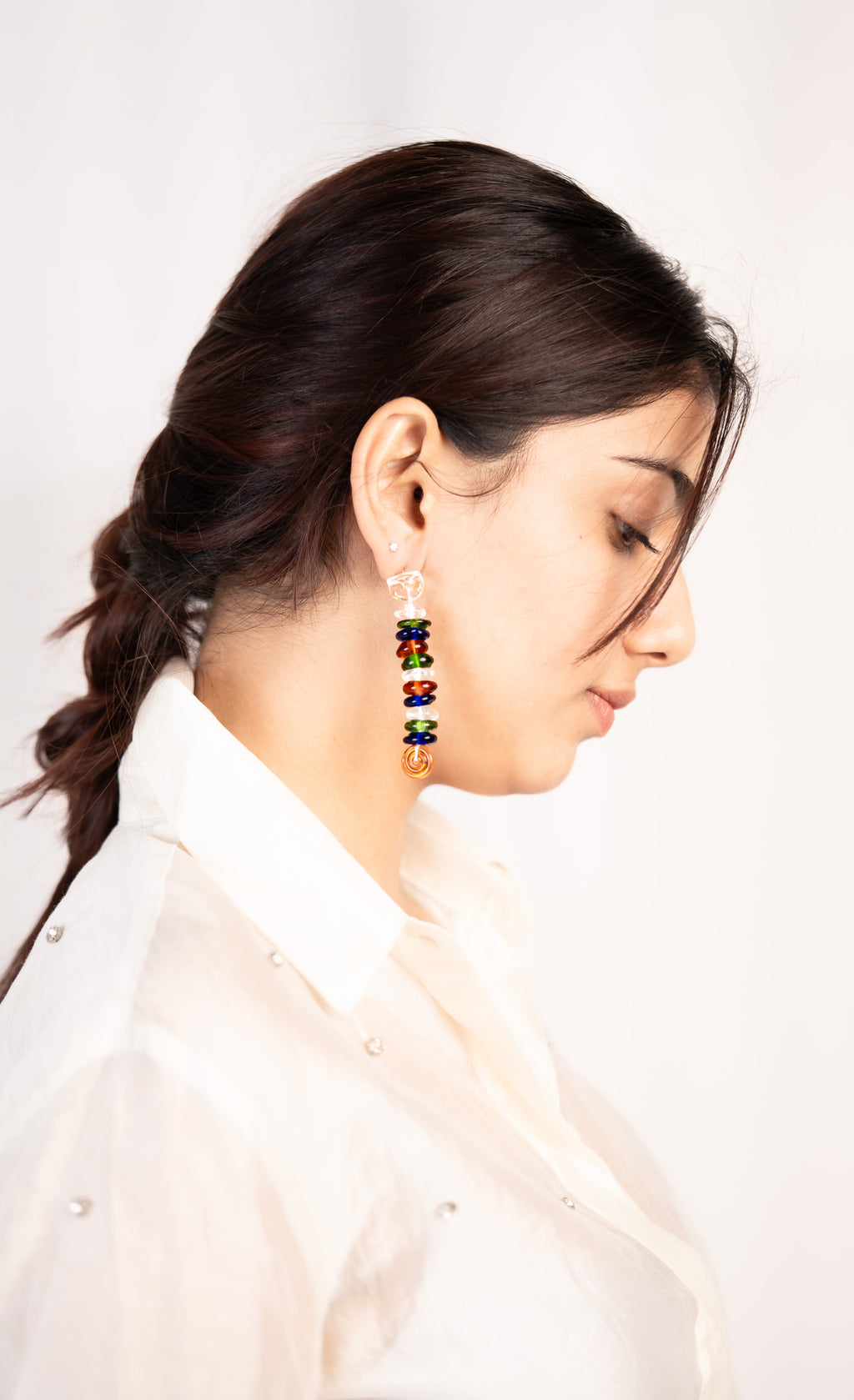 Woman wearing colorful earrings with a plain background