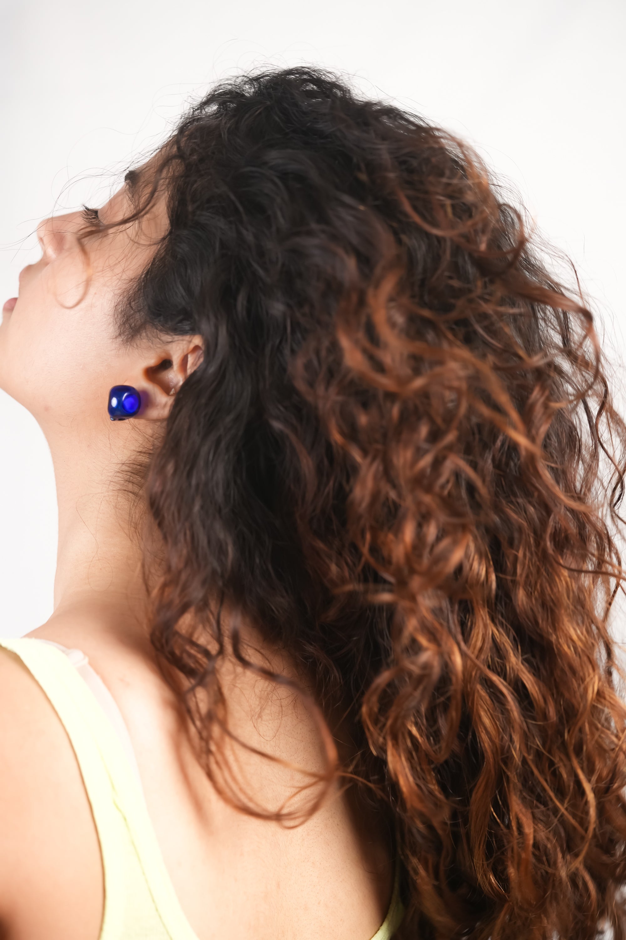 Model wearing handmade borosilicate glass studs in blue by AIROKAD STUDIO.
