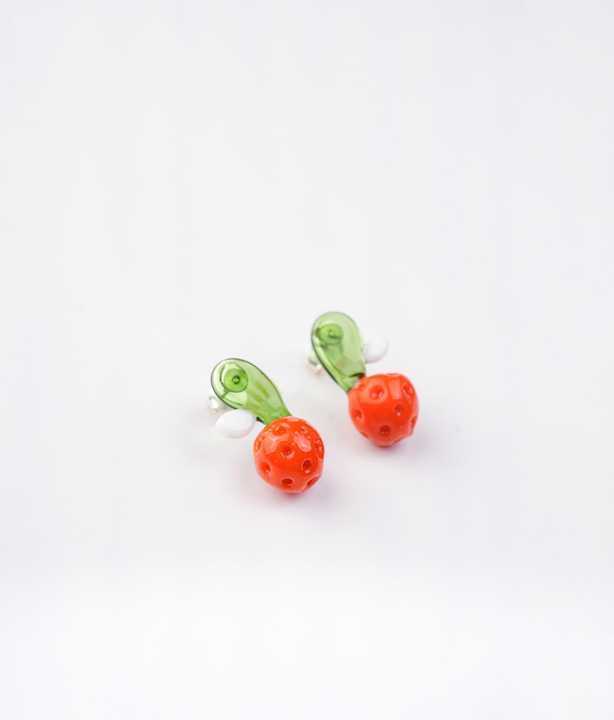Handmade borosilicate glass orange studs with green and white detailing by AIROKAD STUDIO.
