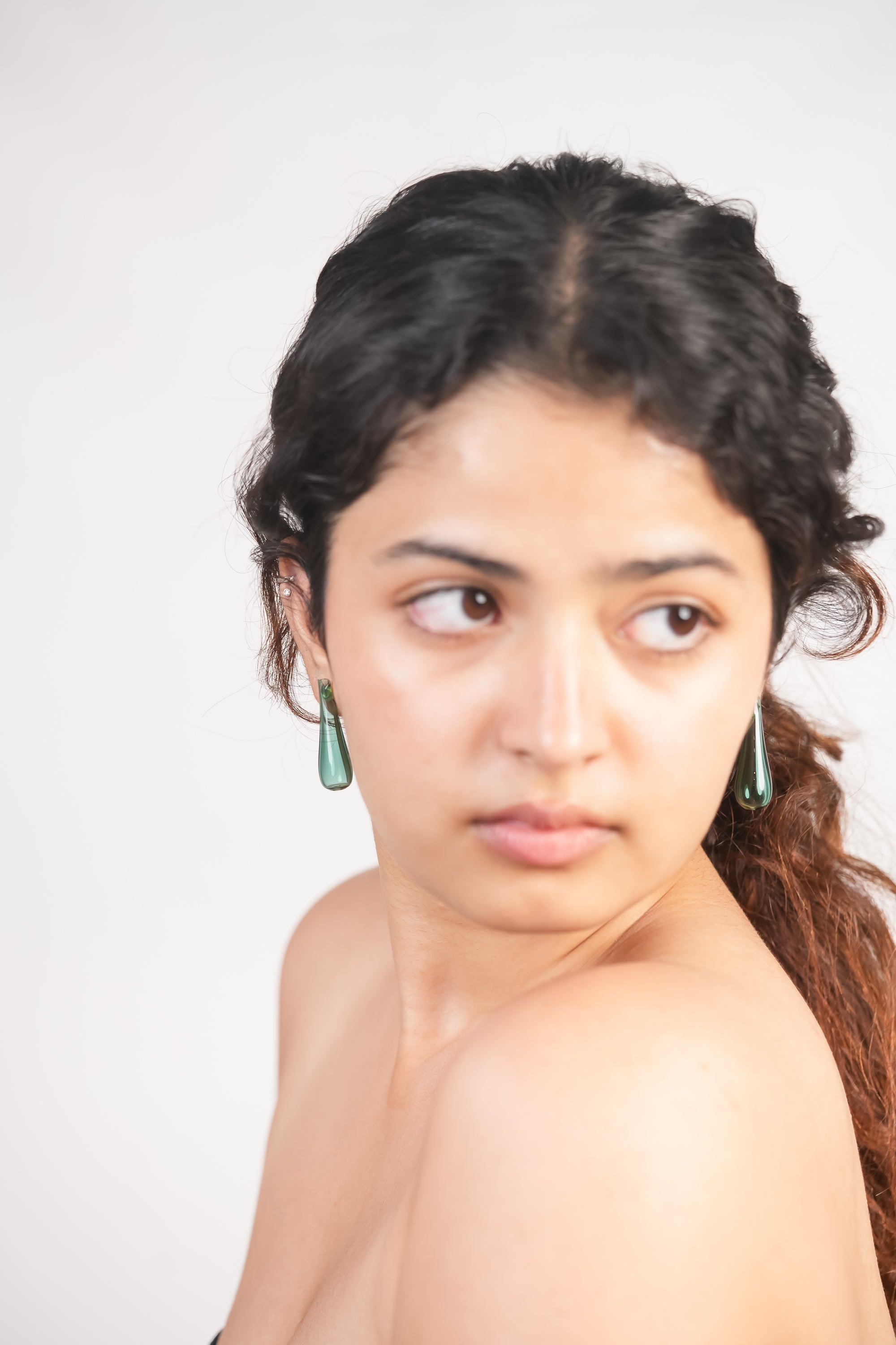 Model wearing tear drop shaped handmade borosilicate glass earrings in teal by AIROKAD STUDIO. 