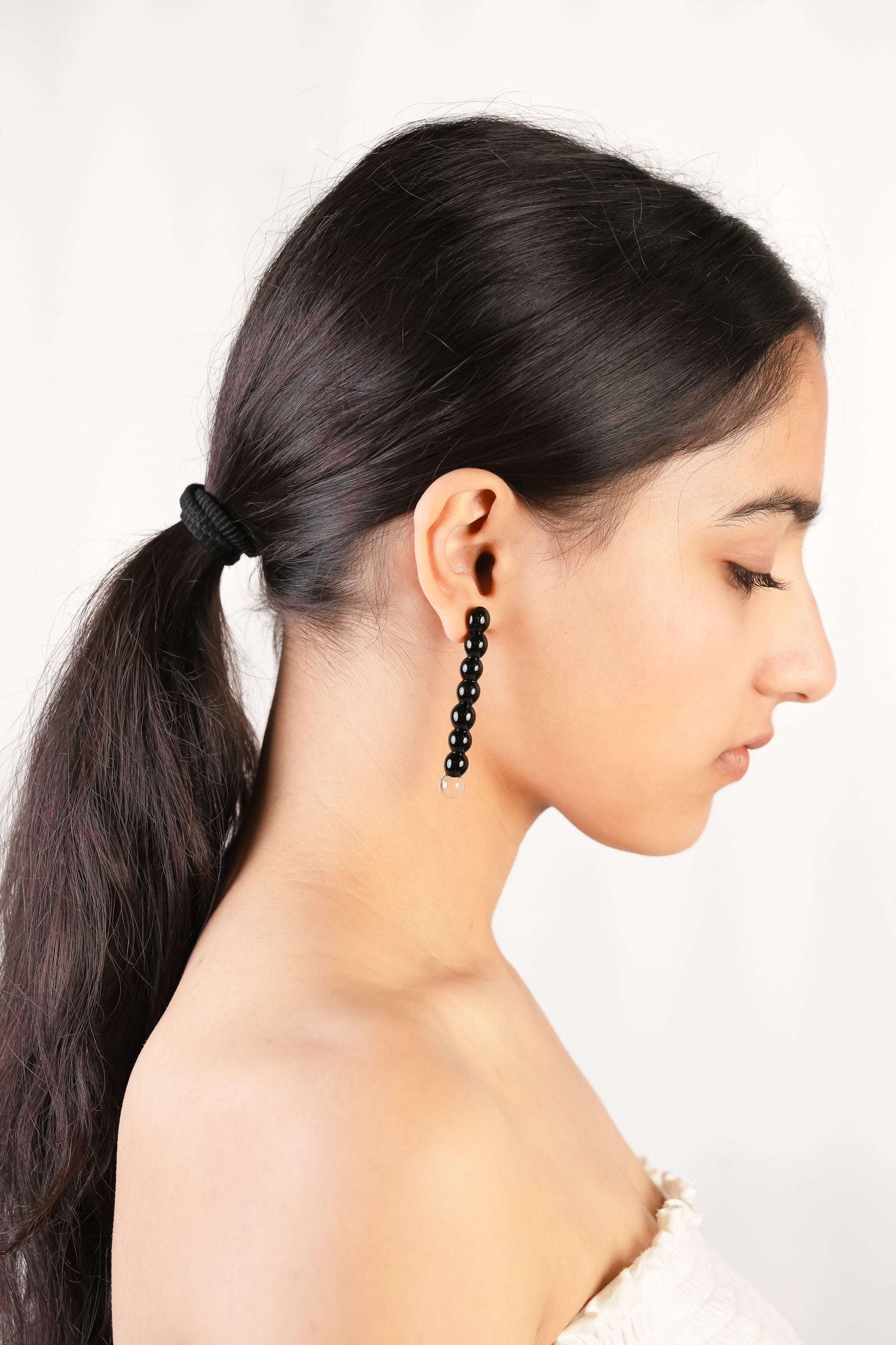 Model wearing handcrafted borosilicate black beaded drop earring with transparent bead detailing by AIROKAD STUDIO.