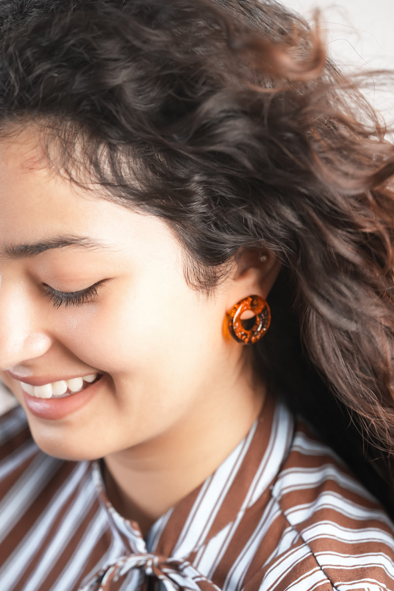 model wearing handmade borosilicate glass circle studs in brown by AIROKAD STUDIO.