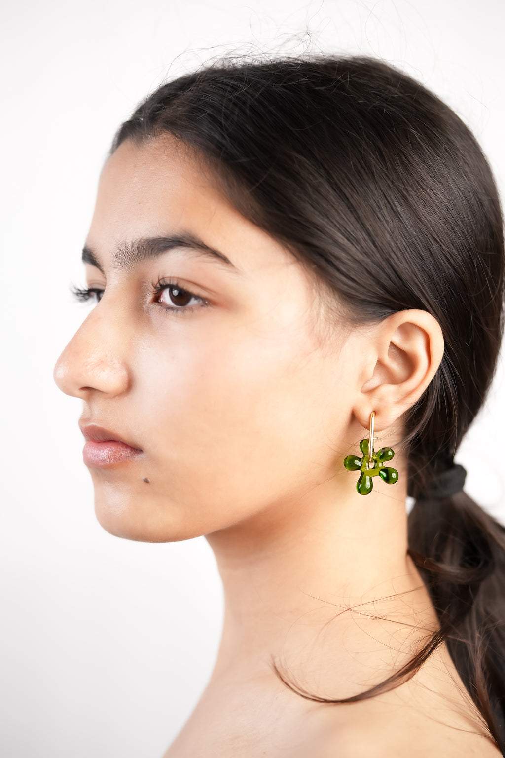 Model wearing handcrafted borosilicate glass flower shaped earrings green by AIROKAD STUDIO.