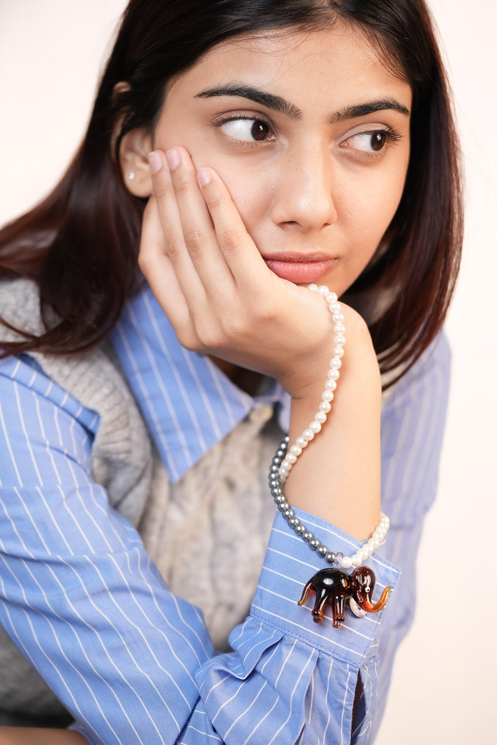 Model wrapping around her hand handcrafted borosilicate glass elephant pendant and 2-color pearls necklace by AIROKAD STUDIO.