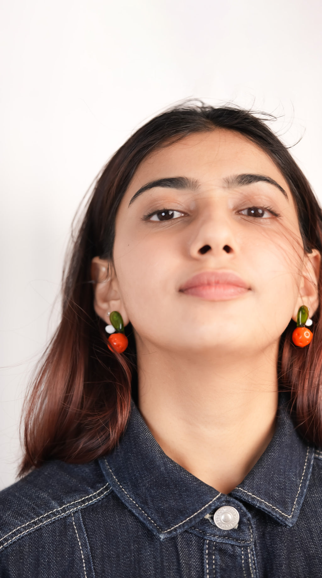 Model wearing vibrant orange glass studs handmade from borosilicate glass by AIROKAD STUDIO. 