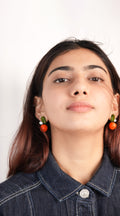Model wearing vibrant orange glass studs handmade from borosilicate glass by AIROKAD STUDIO. 