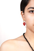 model wearing handcrafted borosilicate glass heart shaped earrings in red with white dots by AIROKAD STUDIO.